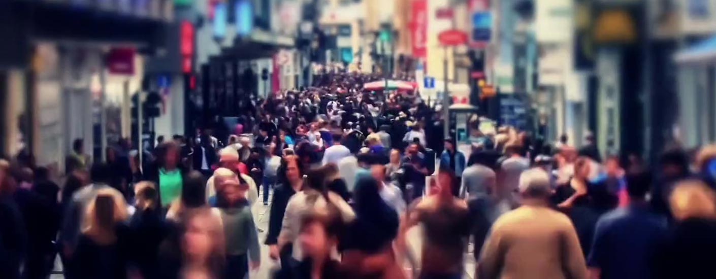 Pedestrian shopping mall with crowds of people walking.