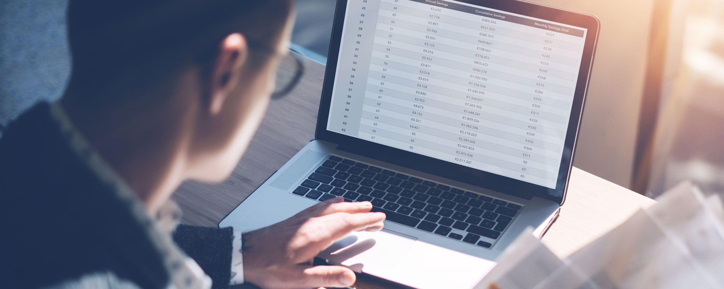 Analyst in eyeglasses working at sunny office on laptop